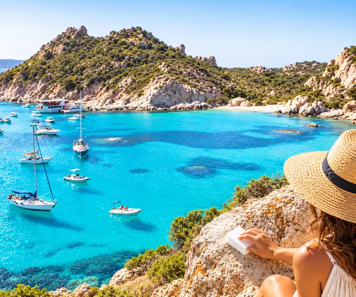 Turquoise coastal landscape dotted with boats beneath rocky hills